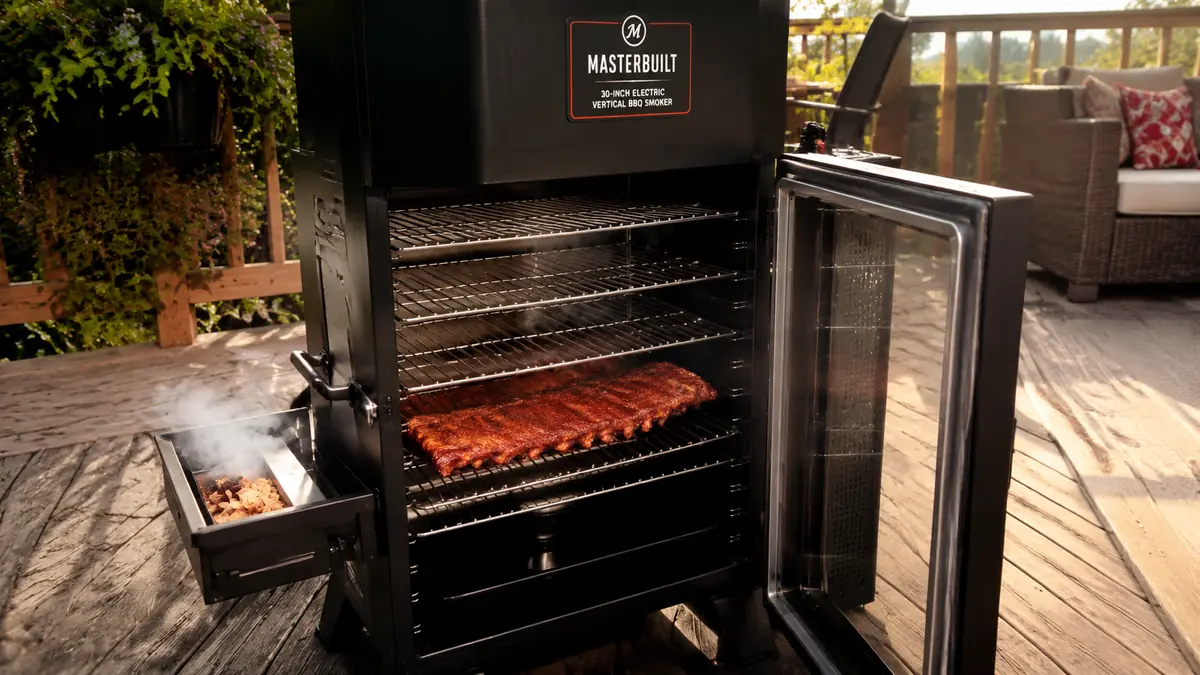 A rack of chrome smoking racks loaded with ribs inside the open Masterbuilt smoker cabinet